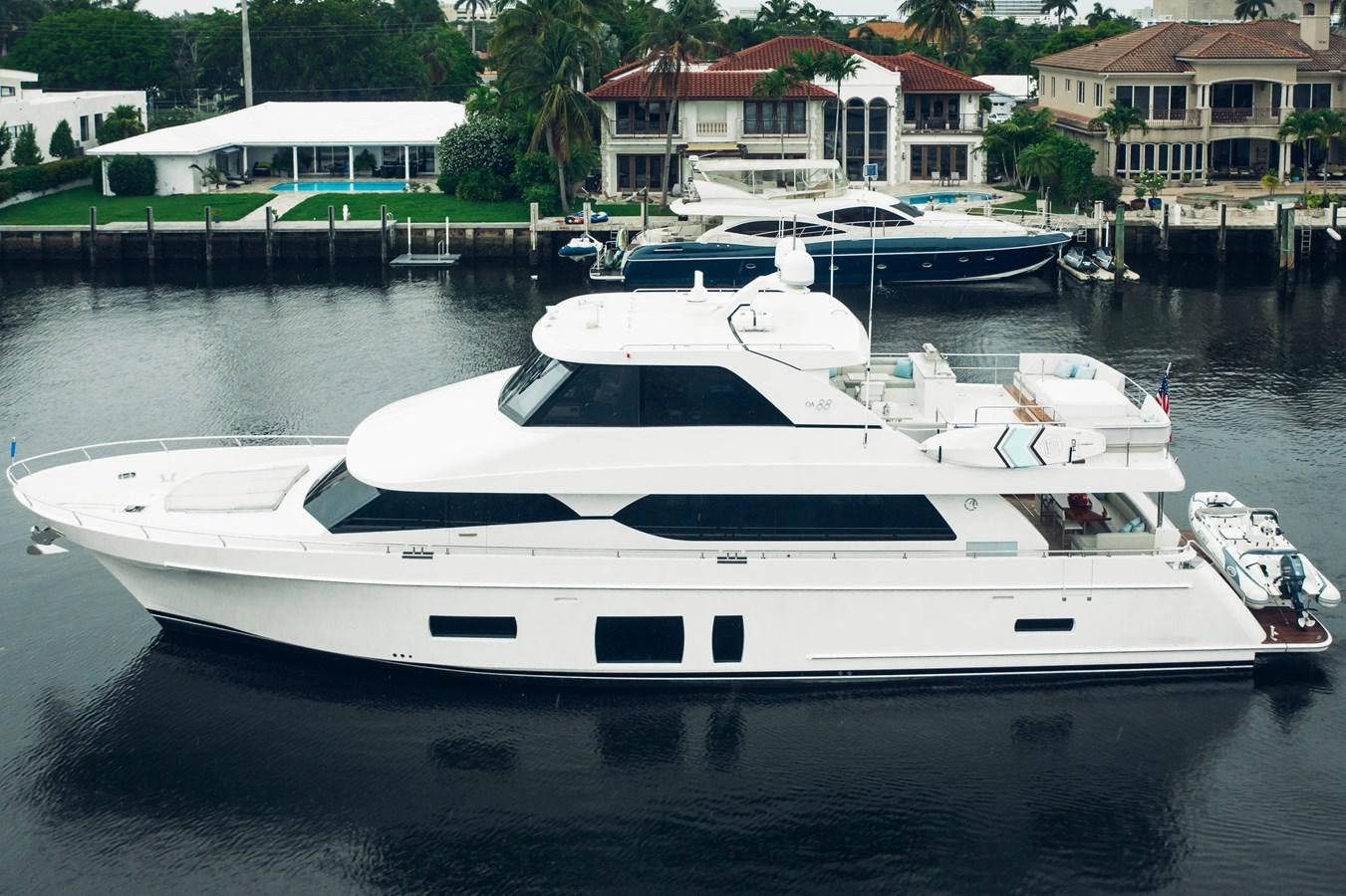 a white yacht in a harbor aboard 2019 OCEAN ALEXANDER 88 SKYLOUNGE MUDSLINGER Yacht for Sale