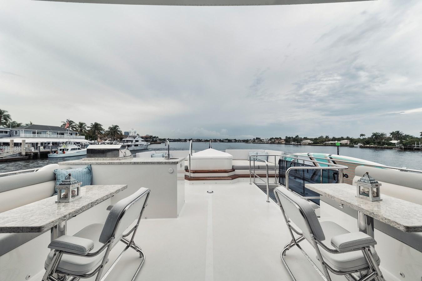 a deck with chairs and tables on it aboard 2019 OCEAN ALEXANDER 88 SKYLOUNGE MUDSLINGER Yacht for Sale