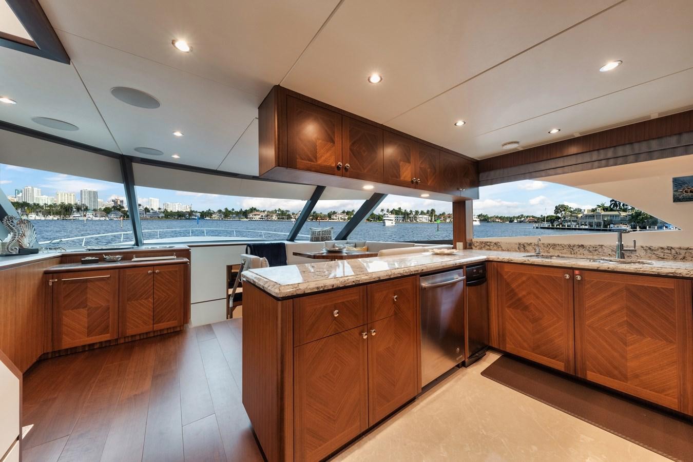 a large kitchen with wooden cabinets aboard 2019 OCEAN ALEXANDER 88 SKYLOUNGE MUDSLINGER Yacht for Sale