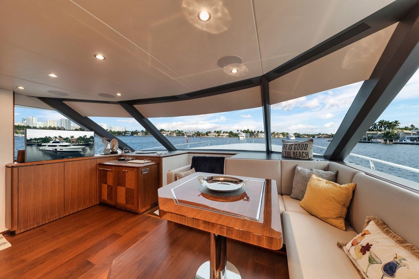 a room with a table and a couch and a window aboard 2019 OCEAN ALEXANDER 88 SKYLOUNGE MUDSLINGER Yacht for Sale