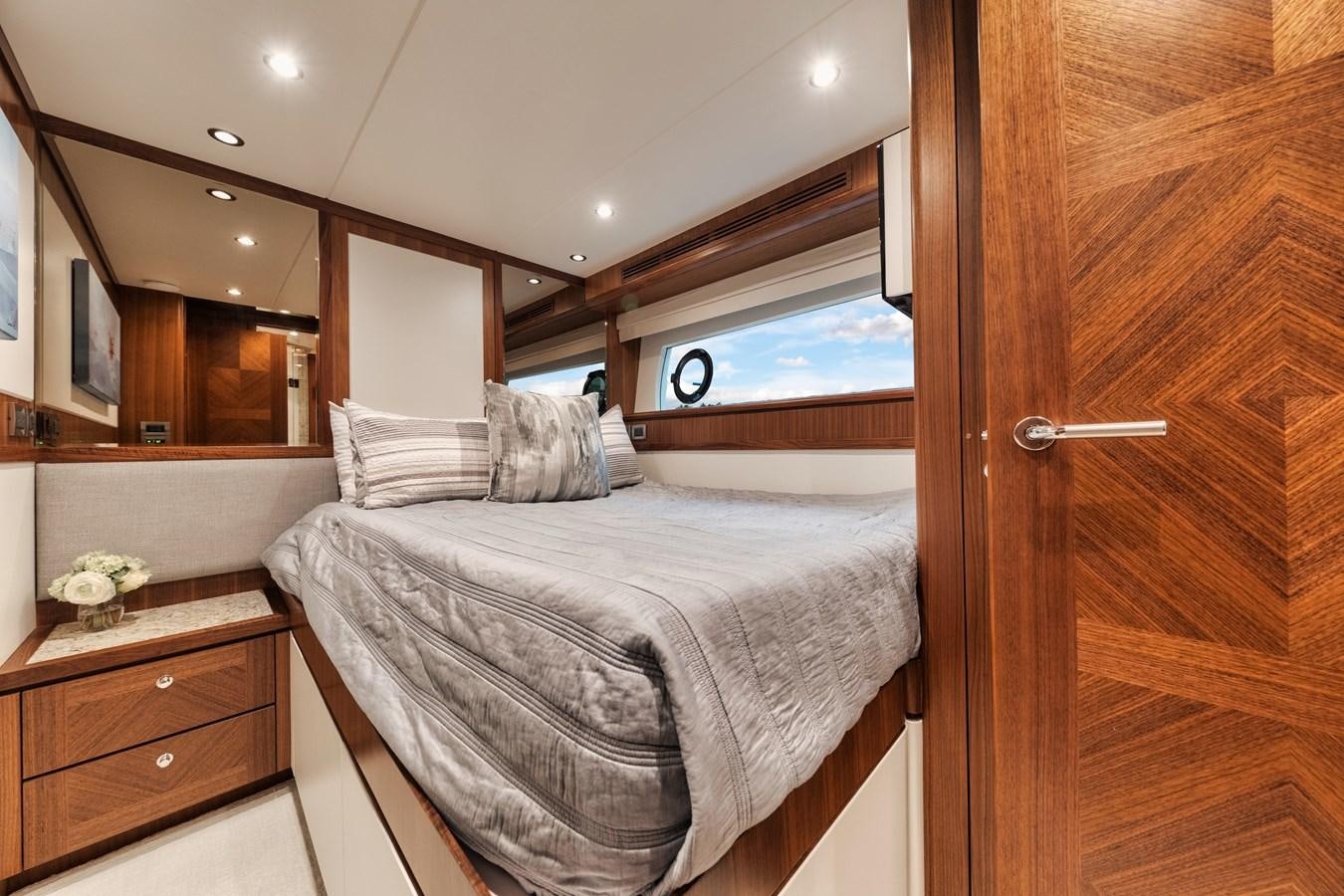 a bedroom with a bed and a wood door aboard 2019 OCEAN ALEXANDER 88 SKYLOUNGE MUDSLINGER Yacht for Sale