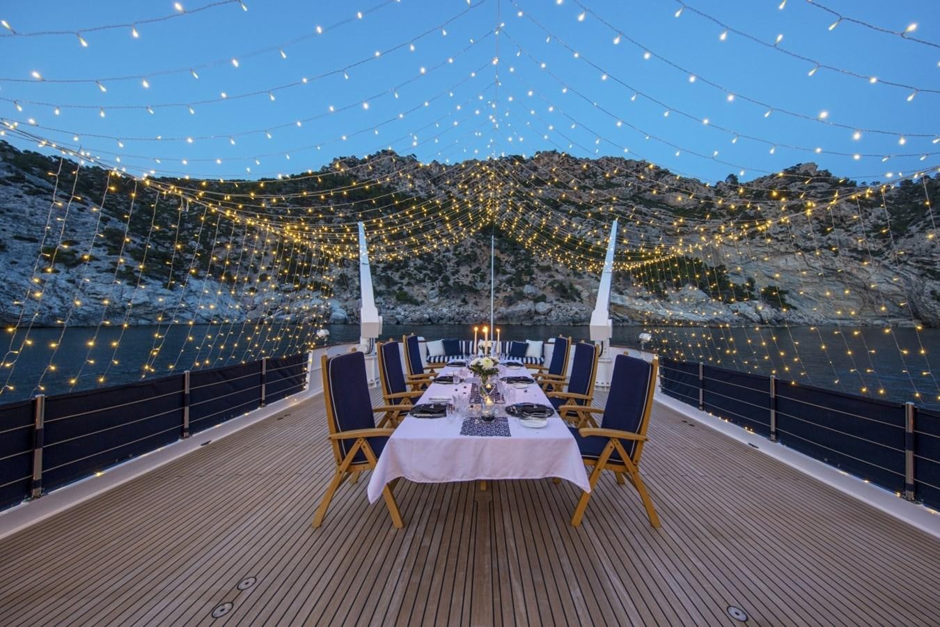 a table and chairs on a deck overlooking a city aboard MONACO Yacht for Sale