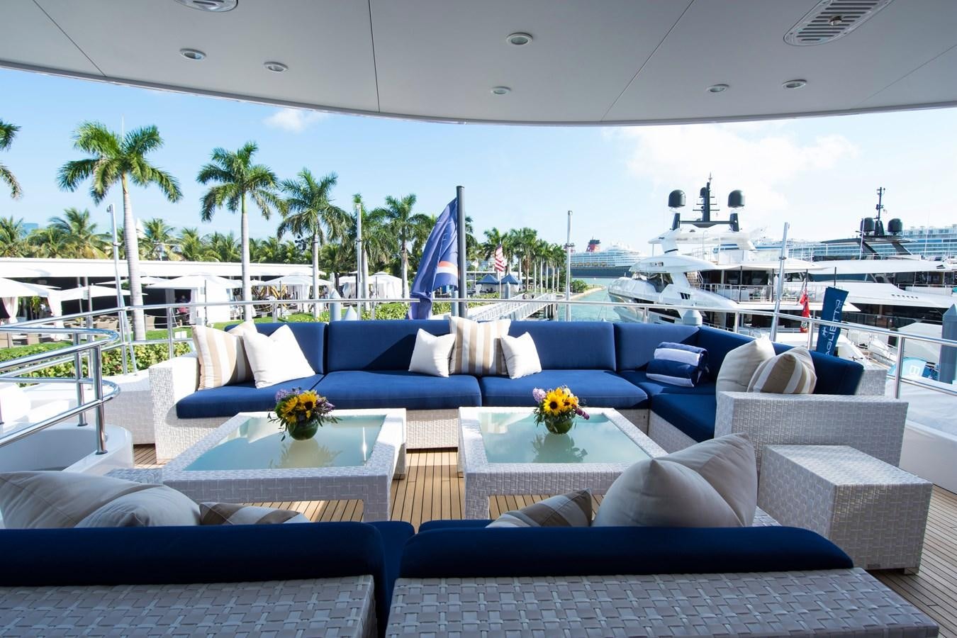 a lounge area with a table and chairs and a large cruise ship in the background aboard HORIZONS II Yacht for Sale
