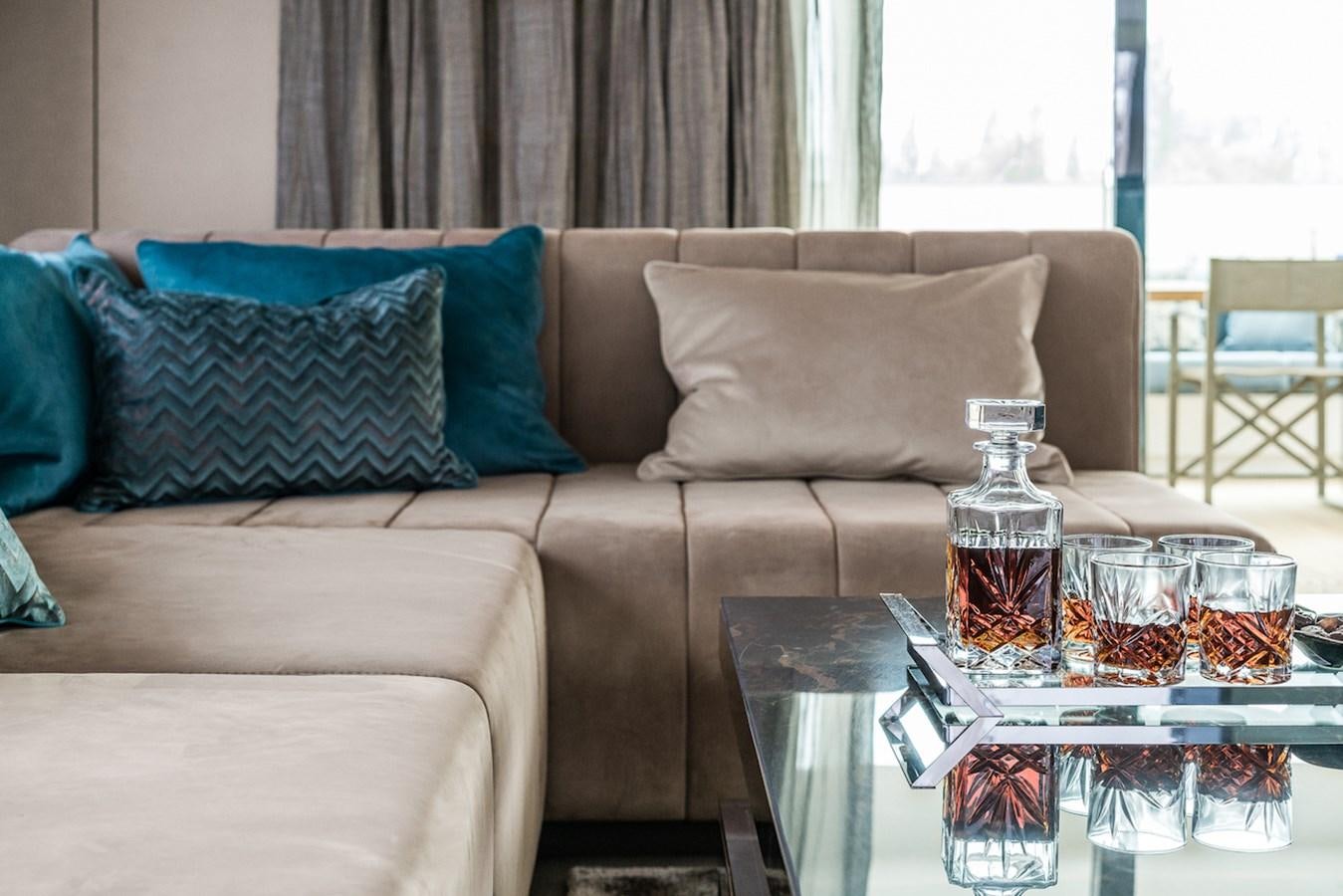 a couch with a glass of beer and a tray of food aboard GIJA Yacht for Sale