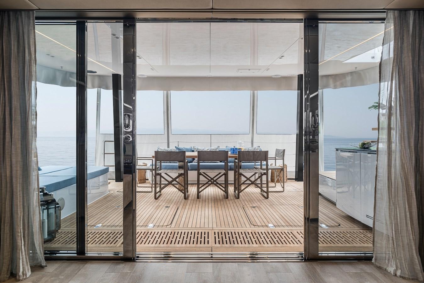 a room with a wood deck and a large window with a view of the ocean aboard GIJA Yacht for Sale
