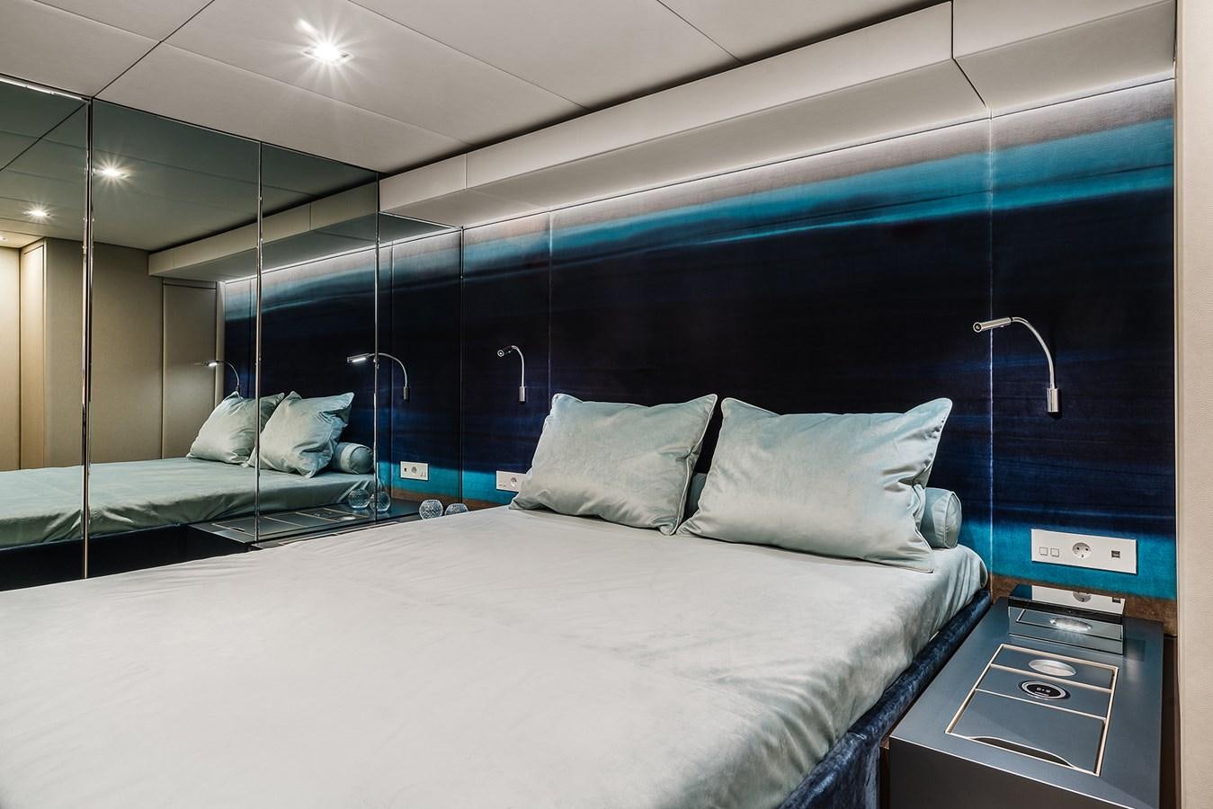 a bed with a blue wall aboard GIJA Yacht for Sale