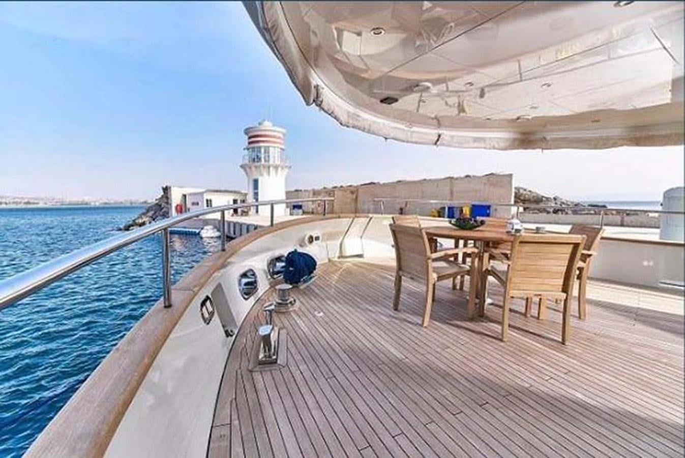 a wooden deck with a table and chairs on it aboard BLUE BERRY Yacht for Sale