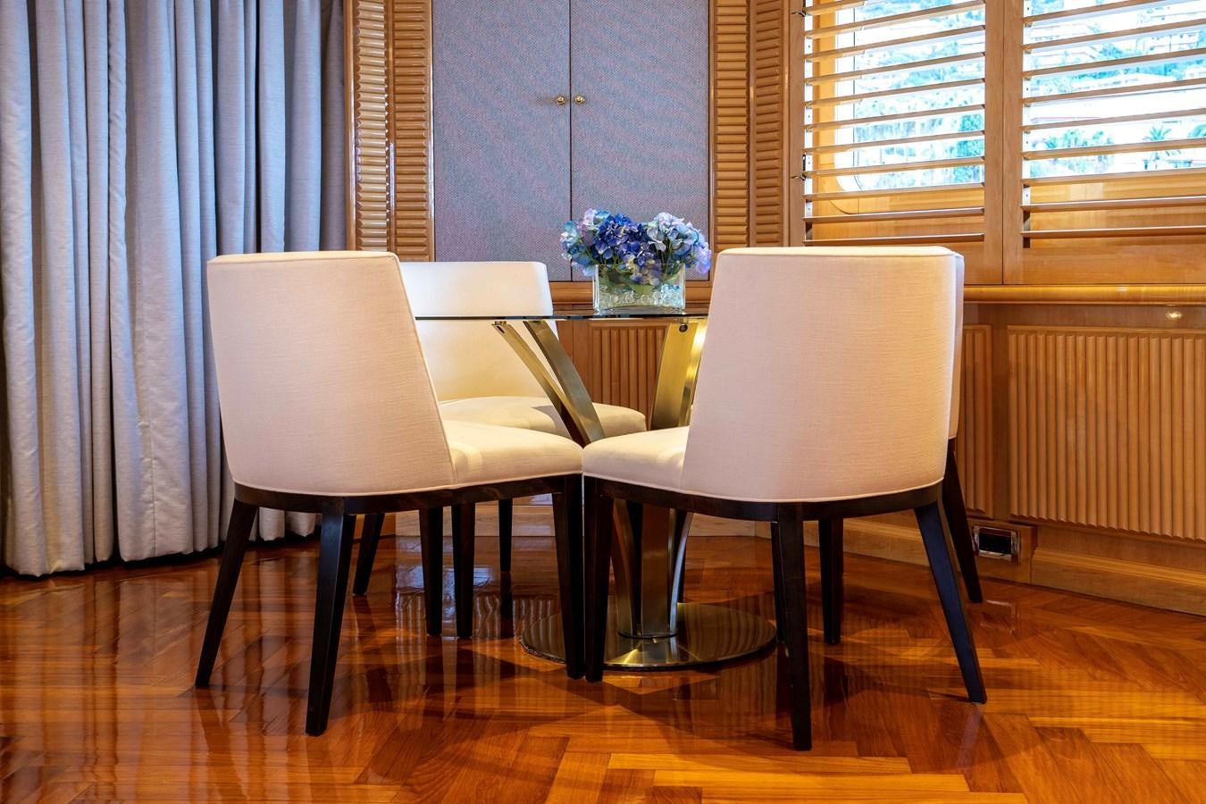 a couple of white chairs in a room with a wood floor aboard TACANUYA Yacht for Charter