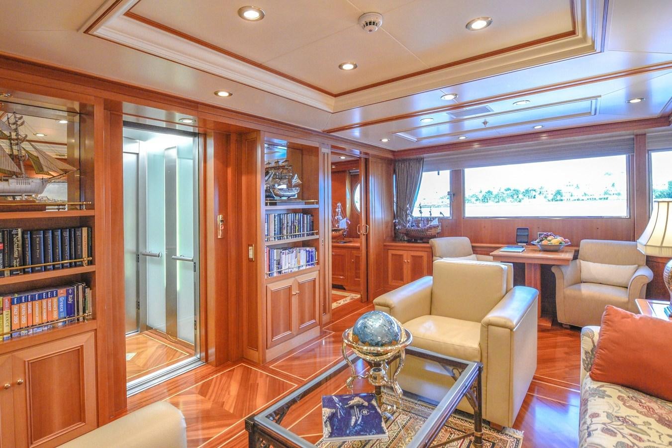 a living room with a glass coffee table and a bookcase aboard TE MANU Yacht for Charter