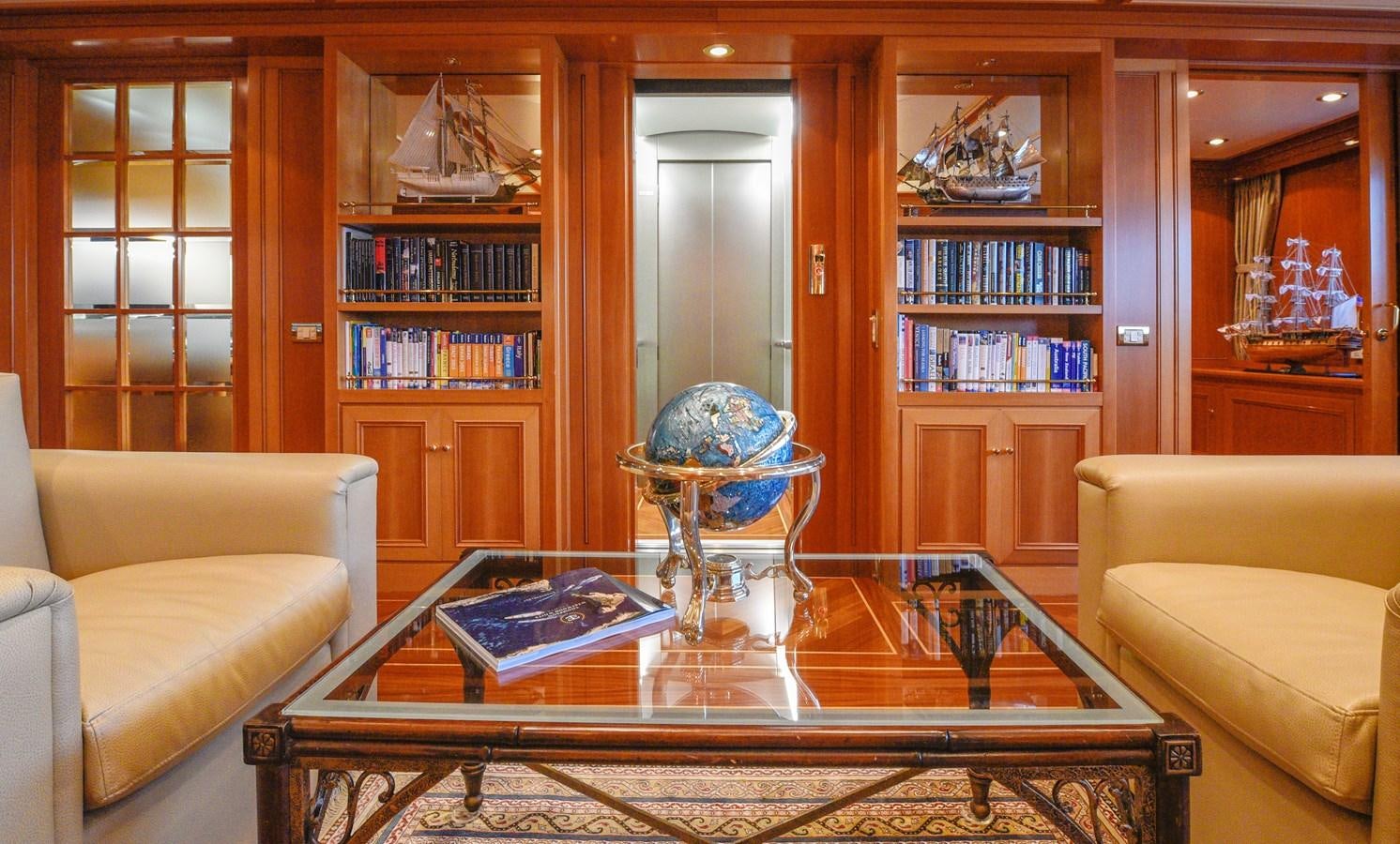 a living room with a glass coffee table and a bookcase aboard TE MANU Yacht for Charter