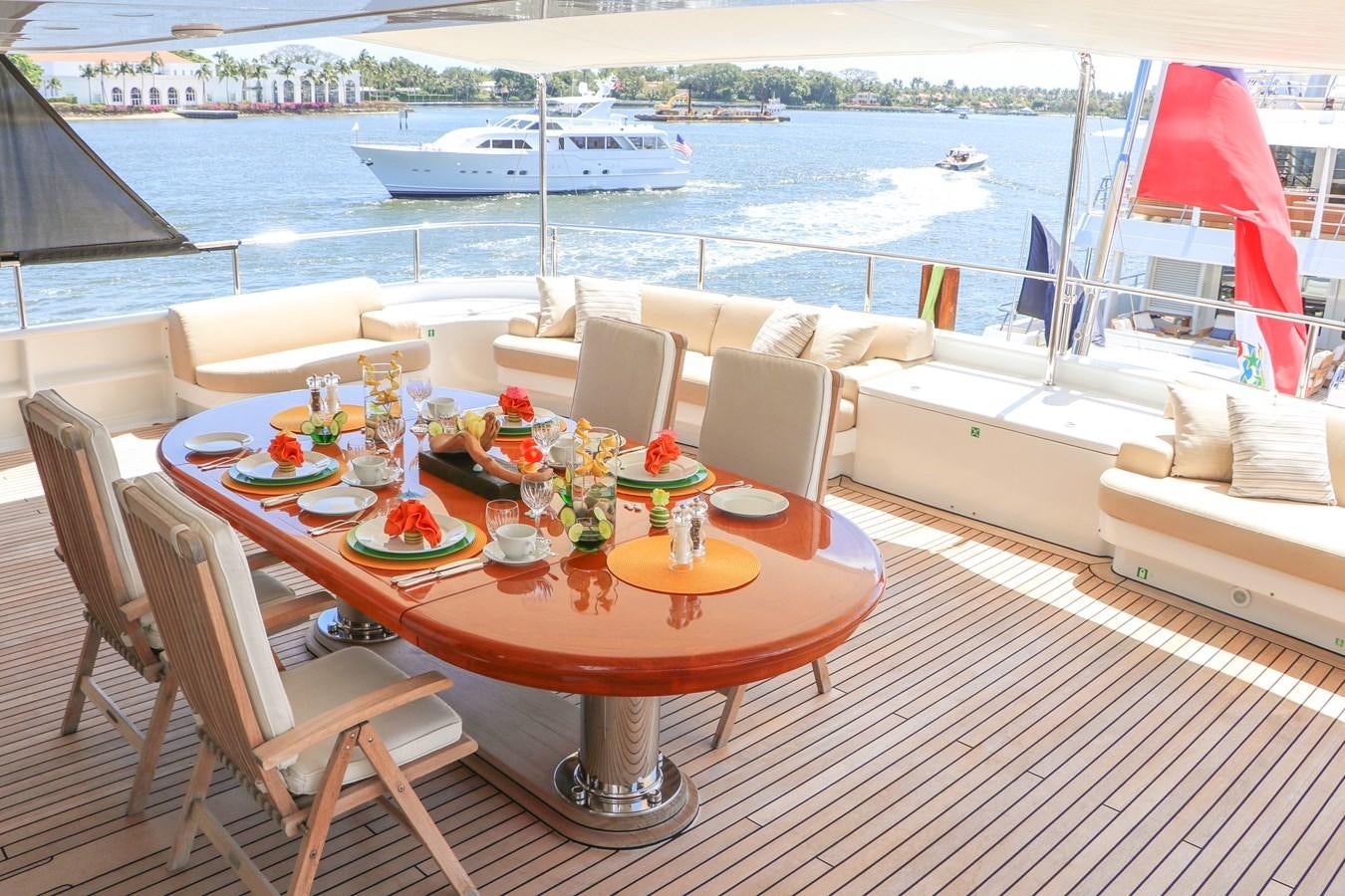 a table set for a meal on a deck overlooking a large ship aboard TE MANU Yacht for Charter