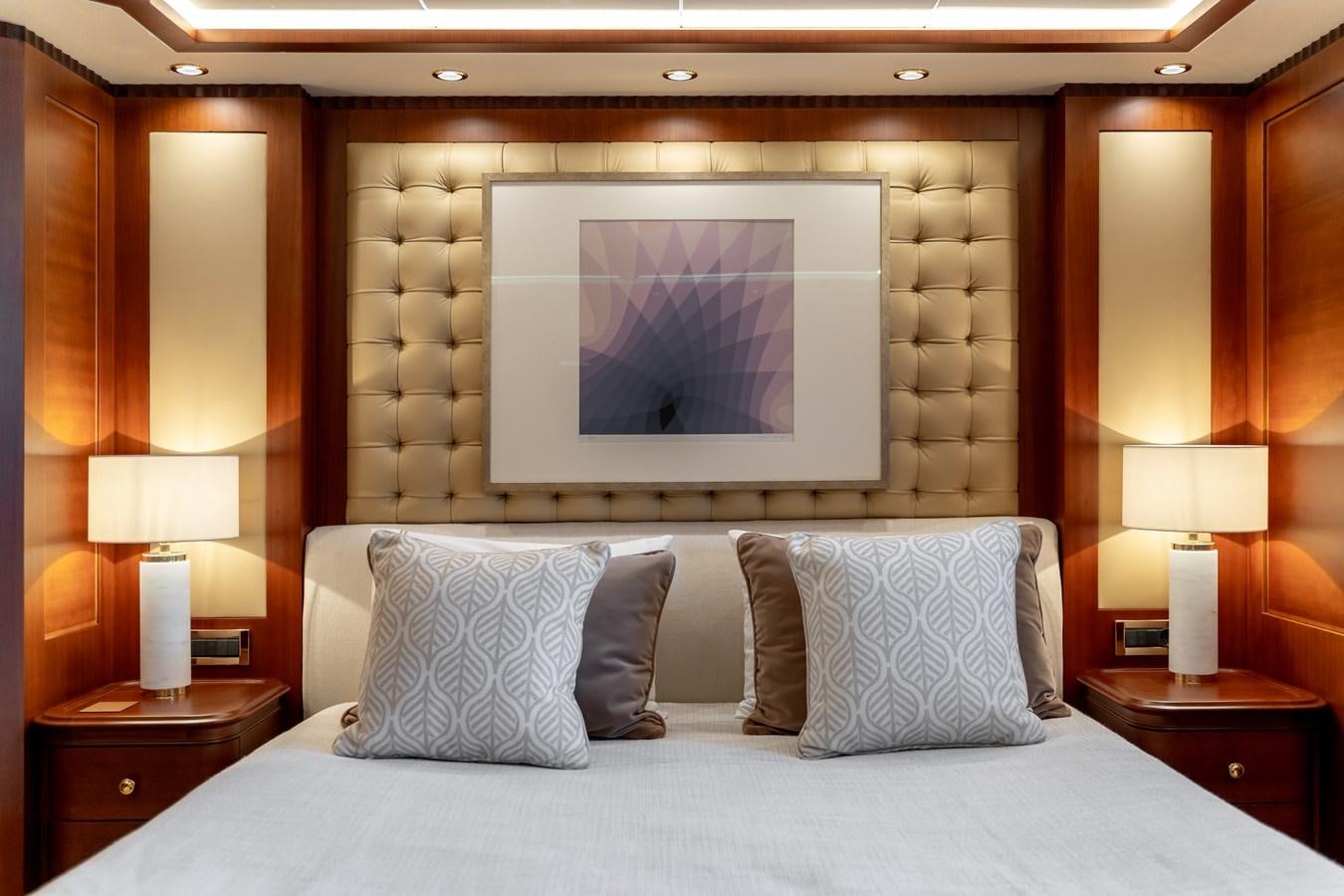a bed with a painting on the wall aboard OCEANOS Yacht for Sale