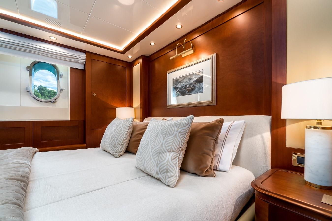 a bed with pillows and a round mirror aboard OCEANOS Yacht for Sale