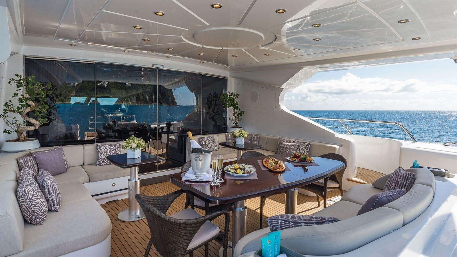 a living room with a large glass window and a table with chairs aboard JOMAR Yacht for Sale