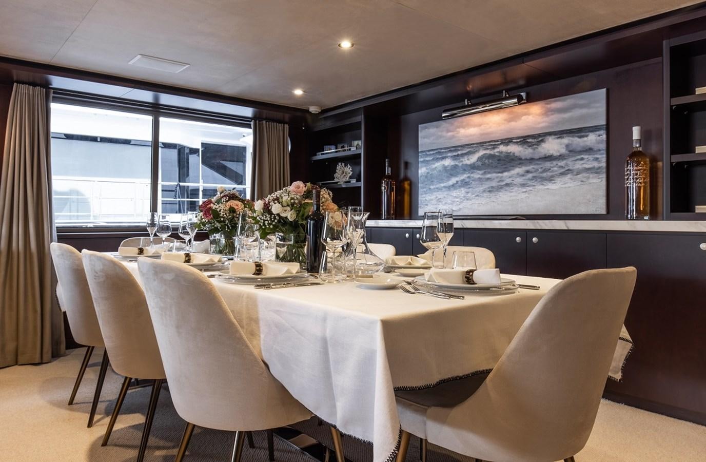 a table with chairs and a large screen in the background aboard CALLISTA Yacht for Sale