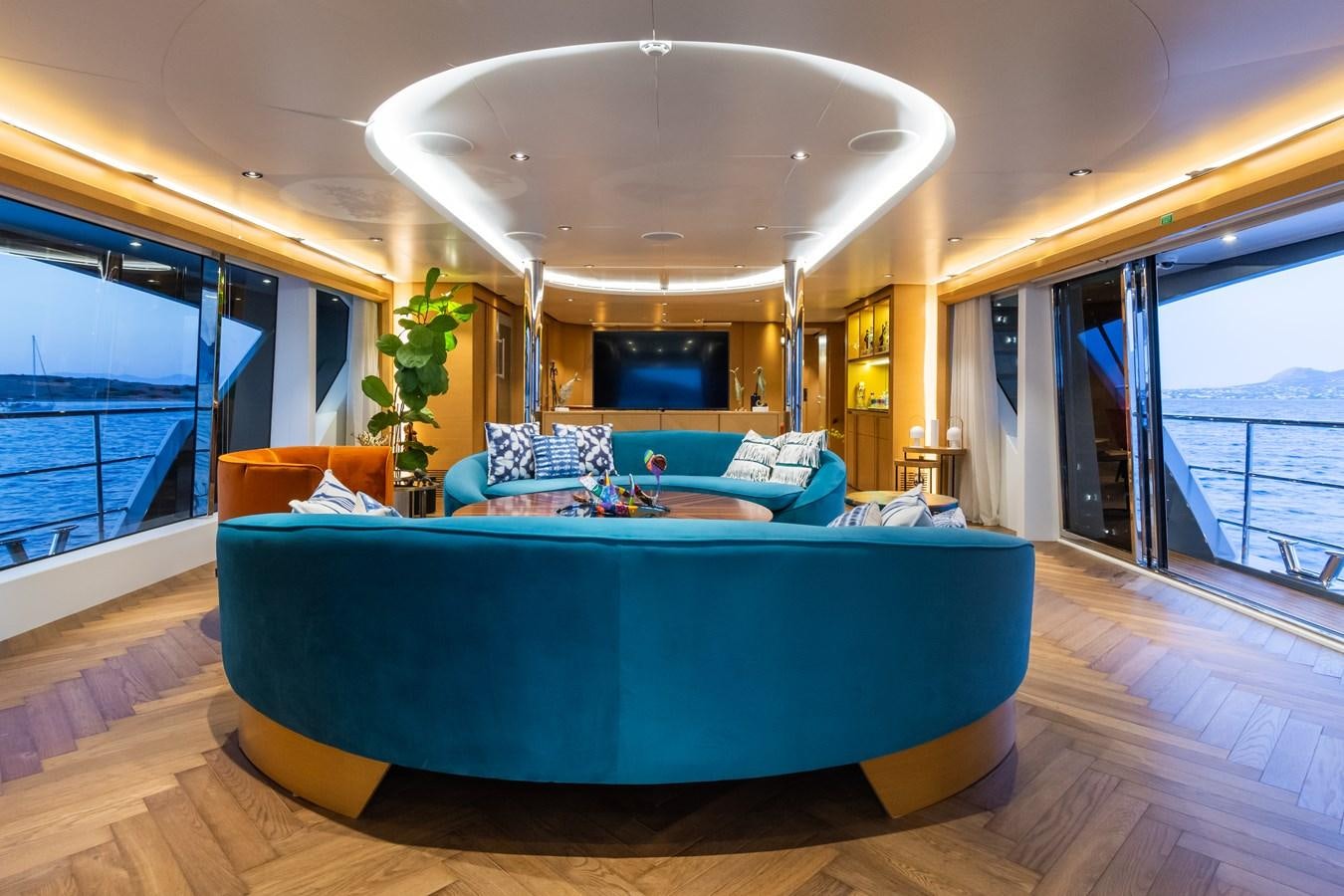 a living room with a large blue couch and a large window aboard LEONIDAS Yacht for Sale