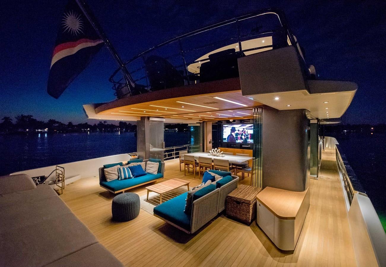 a room with a pool and a deck with a large pool and a large building with a flag aboard CYRA Yacht for Sale