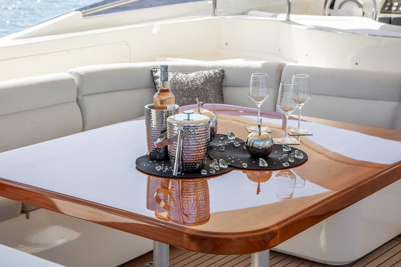 a table with wine glasses and bottles on it aboard THINK BIG Yacht for Sale