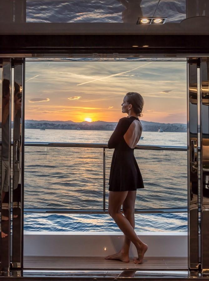 a woman standing on a deck looking out to the sunset aboard PEARL Yacht for Sale