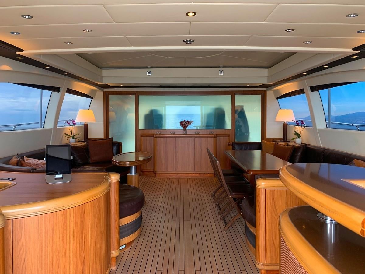 a room with a large television and a table with chairs and a large window aboard LITTLE ZOE Yacht for Sale