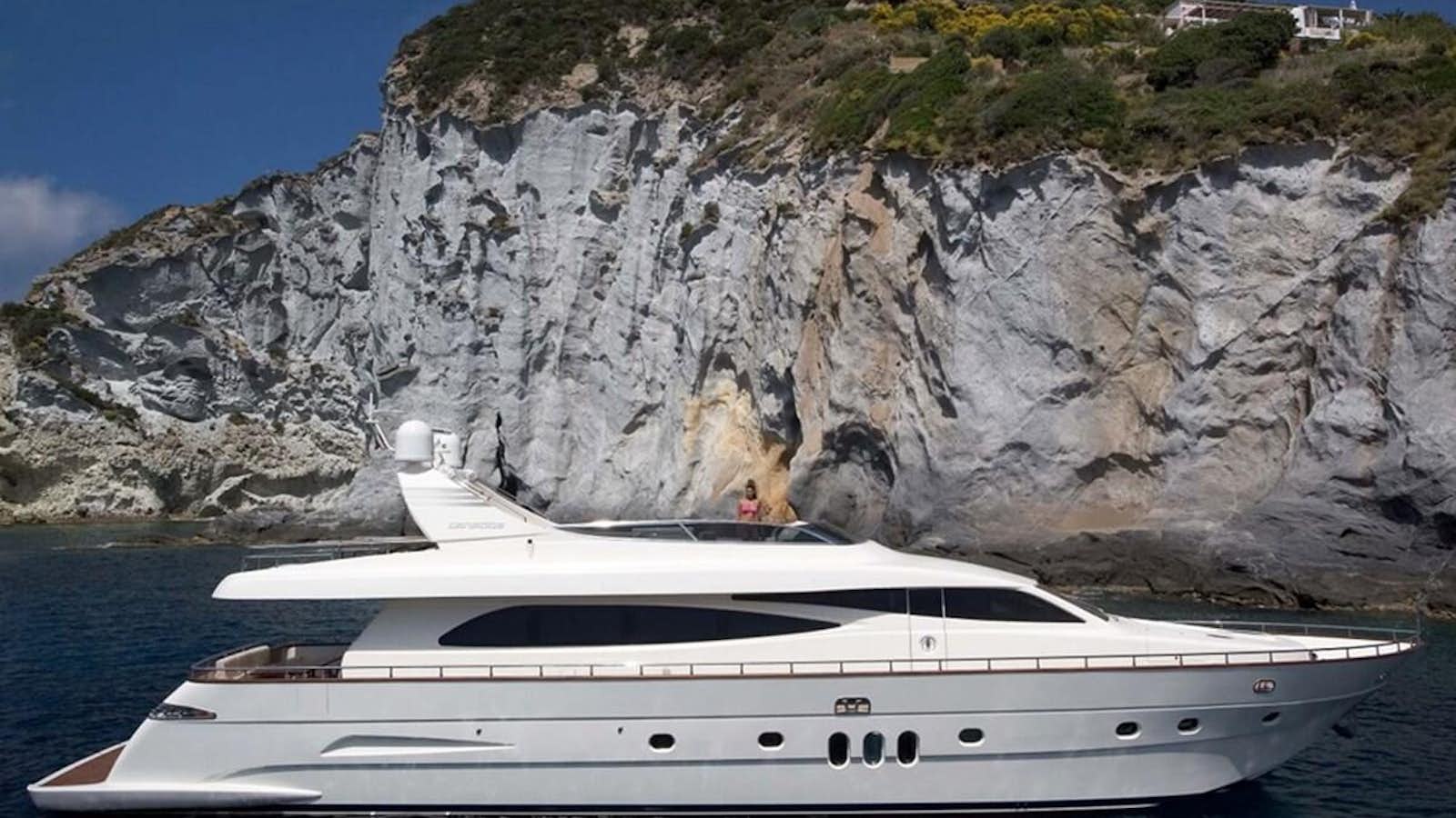 a white yacht in front of a large mountain aboard HABANO Yacht for Sale