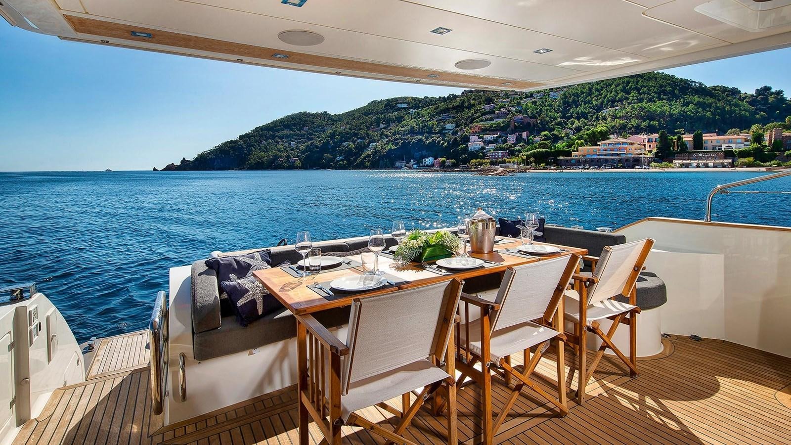 a table and chairs on a deck overlooking a body of water aboard ARMONEE Yacht for Sale