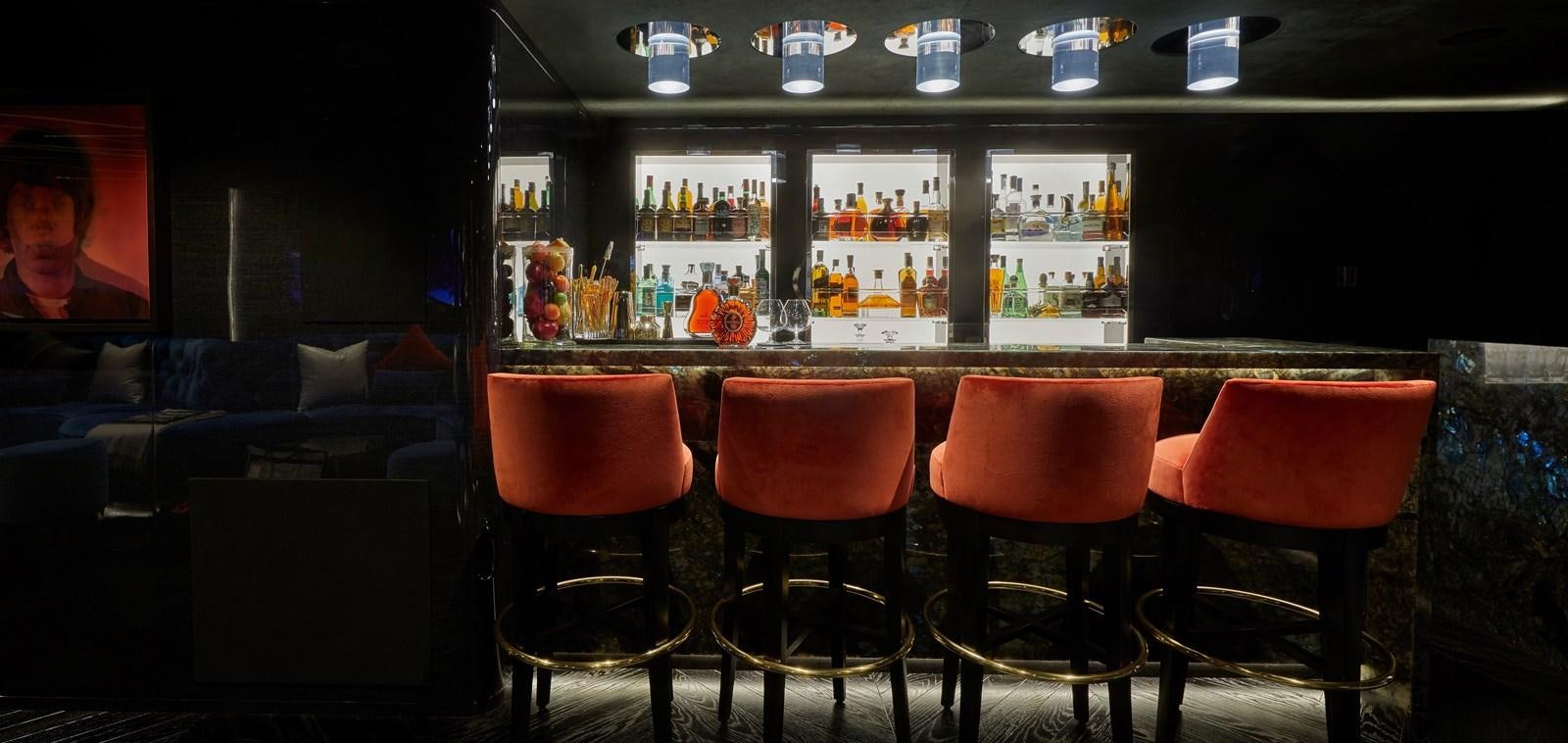 a bar with red chairs and a table with a television on it aboard IJE Yacht for Sale