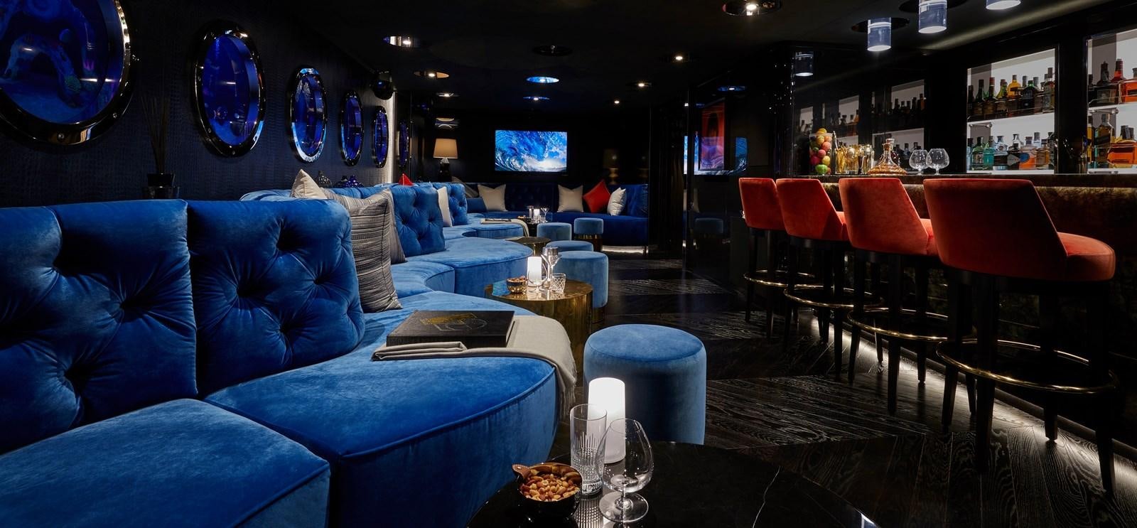 a room with blue couches and chairs aboard IJE Yacht for Sale