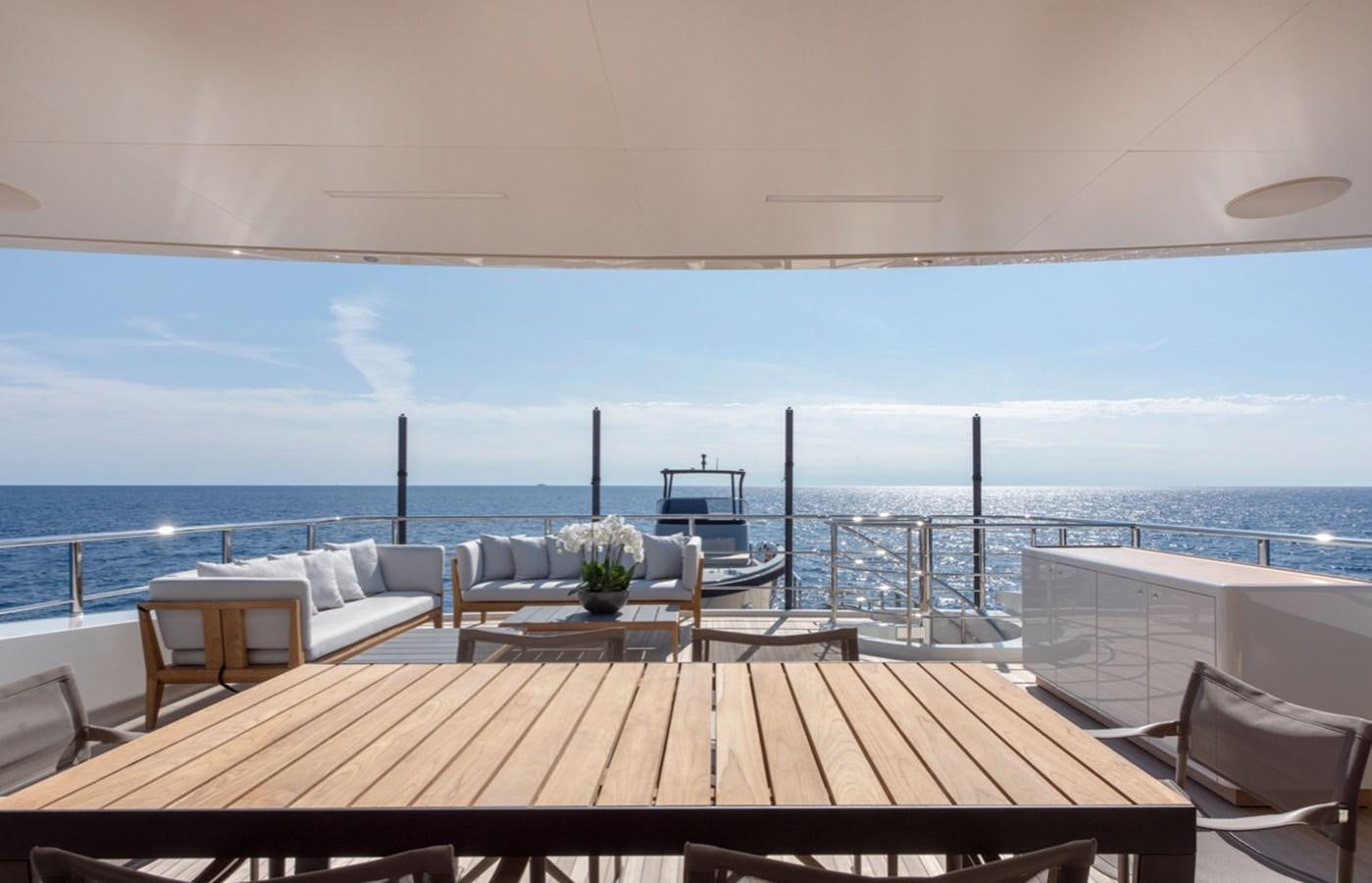 a table and chairs on a deck overlooking a body of water aboard MYKO Yacht for Sale