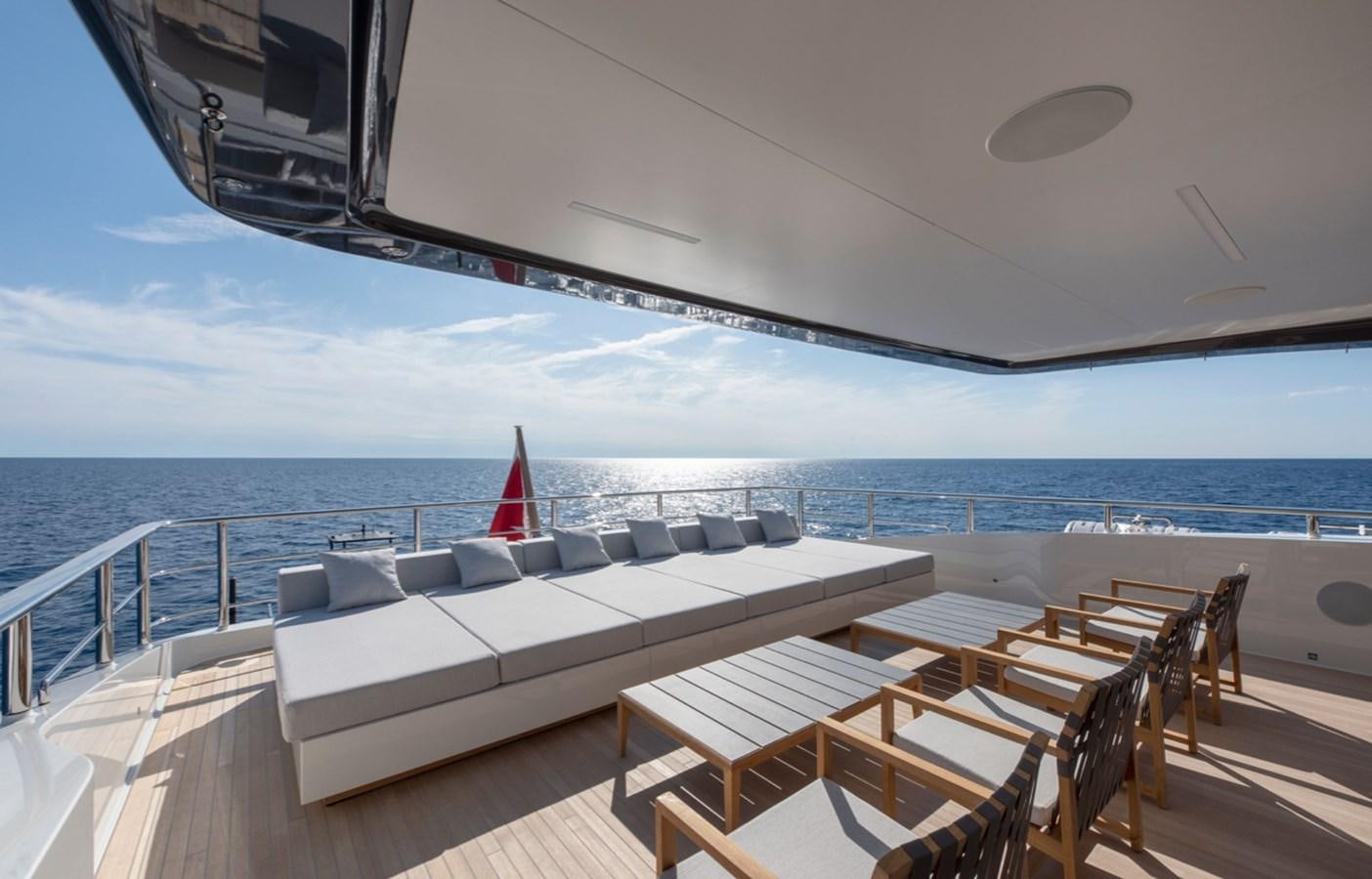 a deck with chairs and tables on it by the ocean aboard MYKO Yacht for Sale