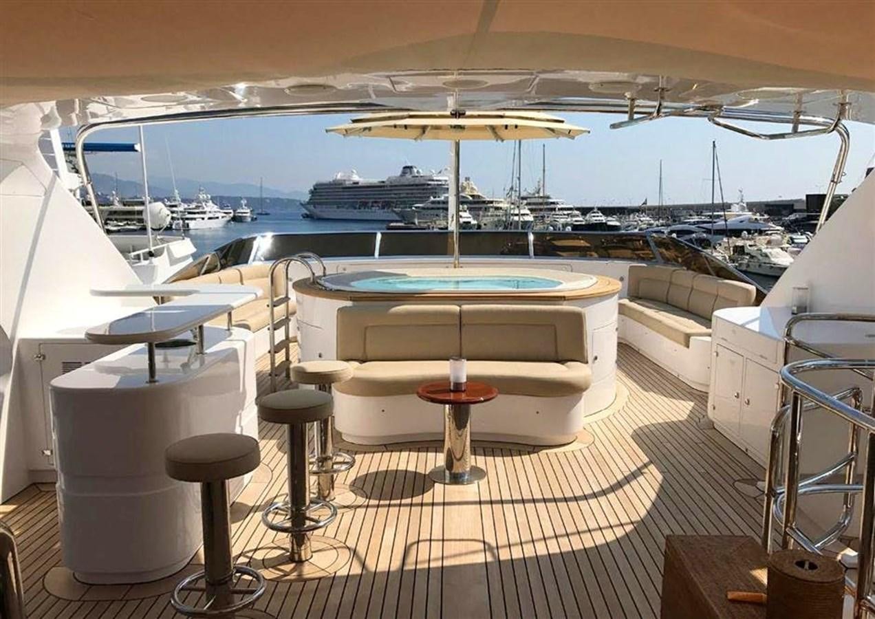 a pool table and chairs on a deck overlooking a large ship aboard VIRTUE Yacht for Sale