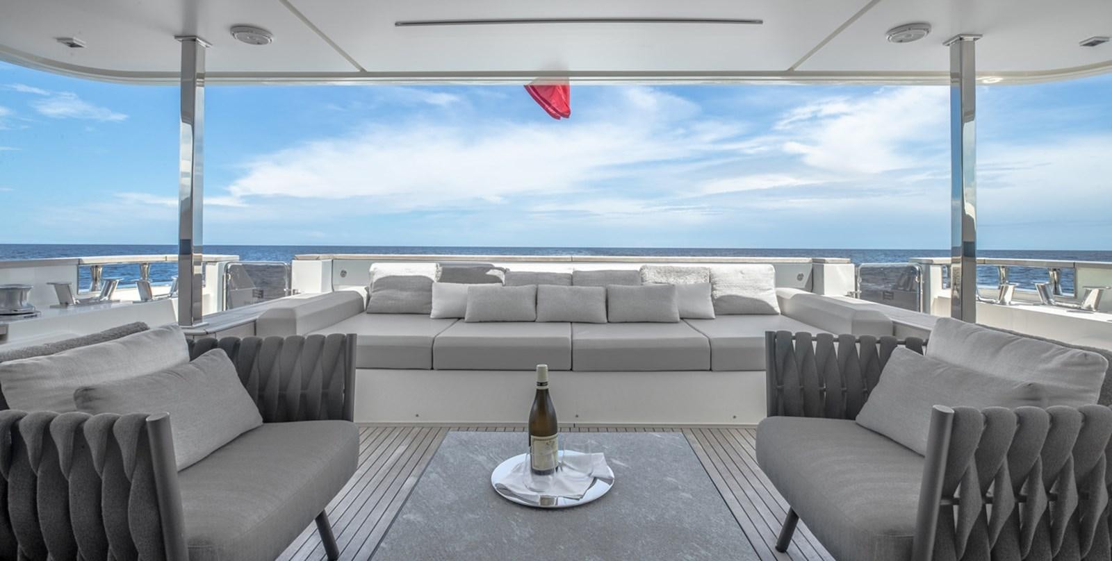 a room with couches and a bottle of wine on a table aboard OCEAN Z Yacht for Sale
