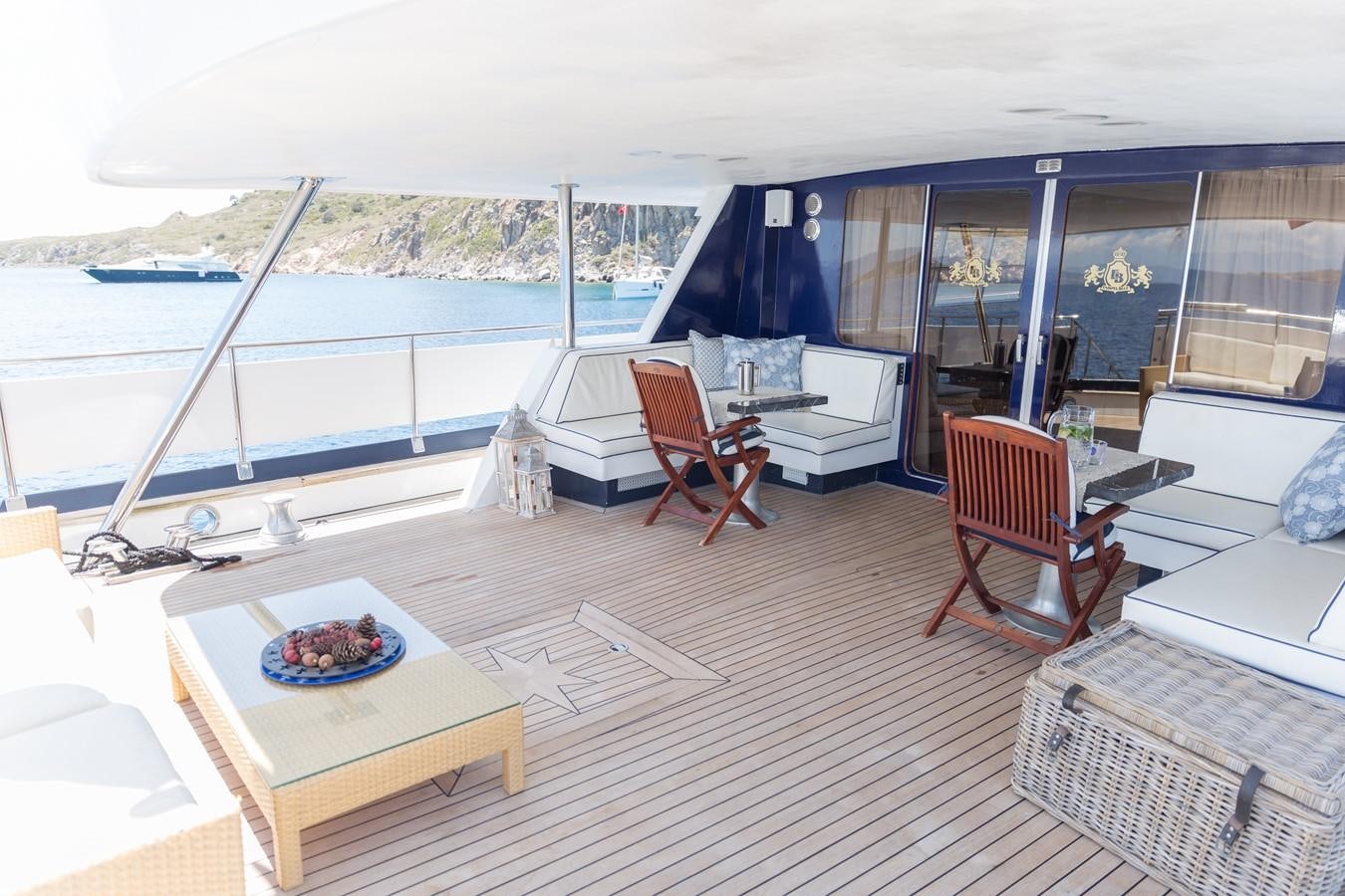 a room with a table chairs and a boat on the water aboard ENIGMA BLUE Yacht for Sale