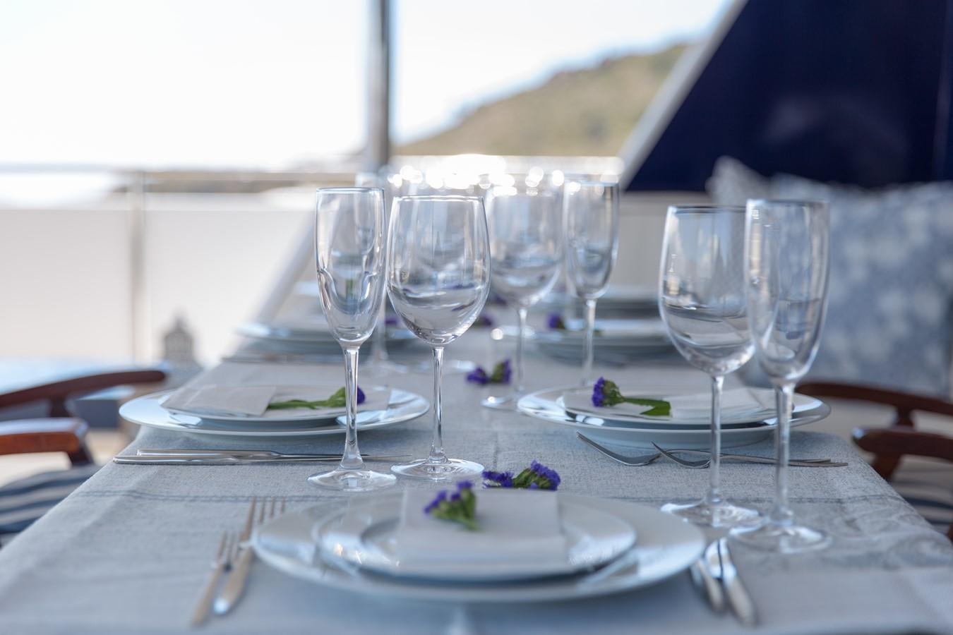 a table with plates and glasses aboard ENIGMA BLUE Yacht for Sale