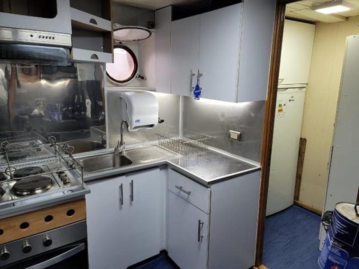 a kitchen with white cabinets aboard 2005 CUSTOM PILOT BOAT Yacht for Sale