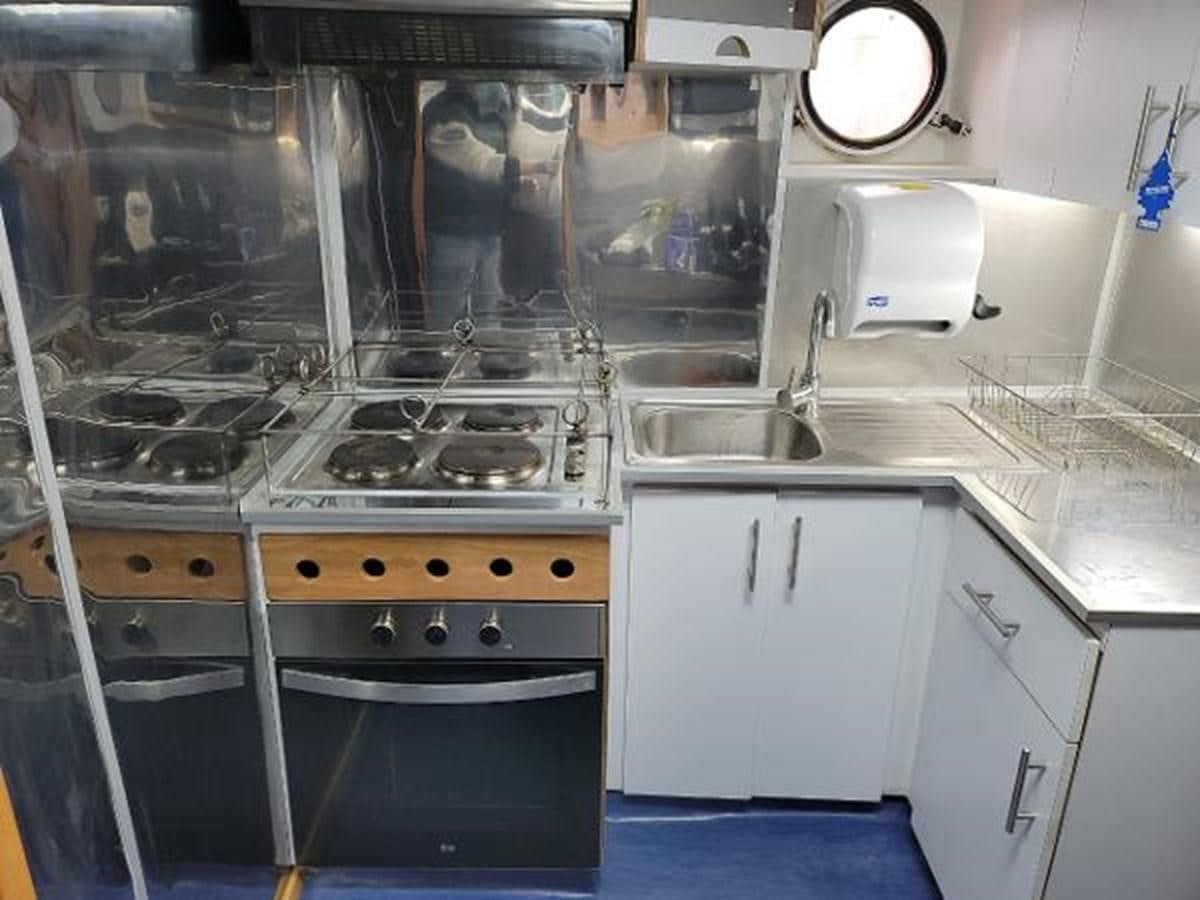 a kitchen with white cabinets aboard 2005 CUSTOM PILOT BOAT Yacht for Sale