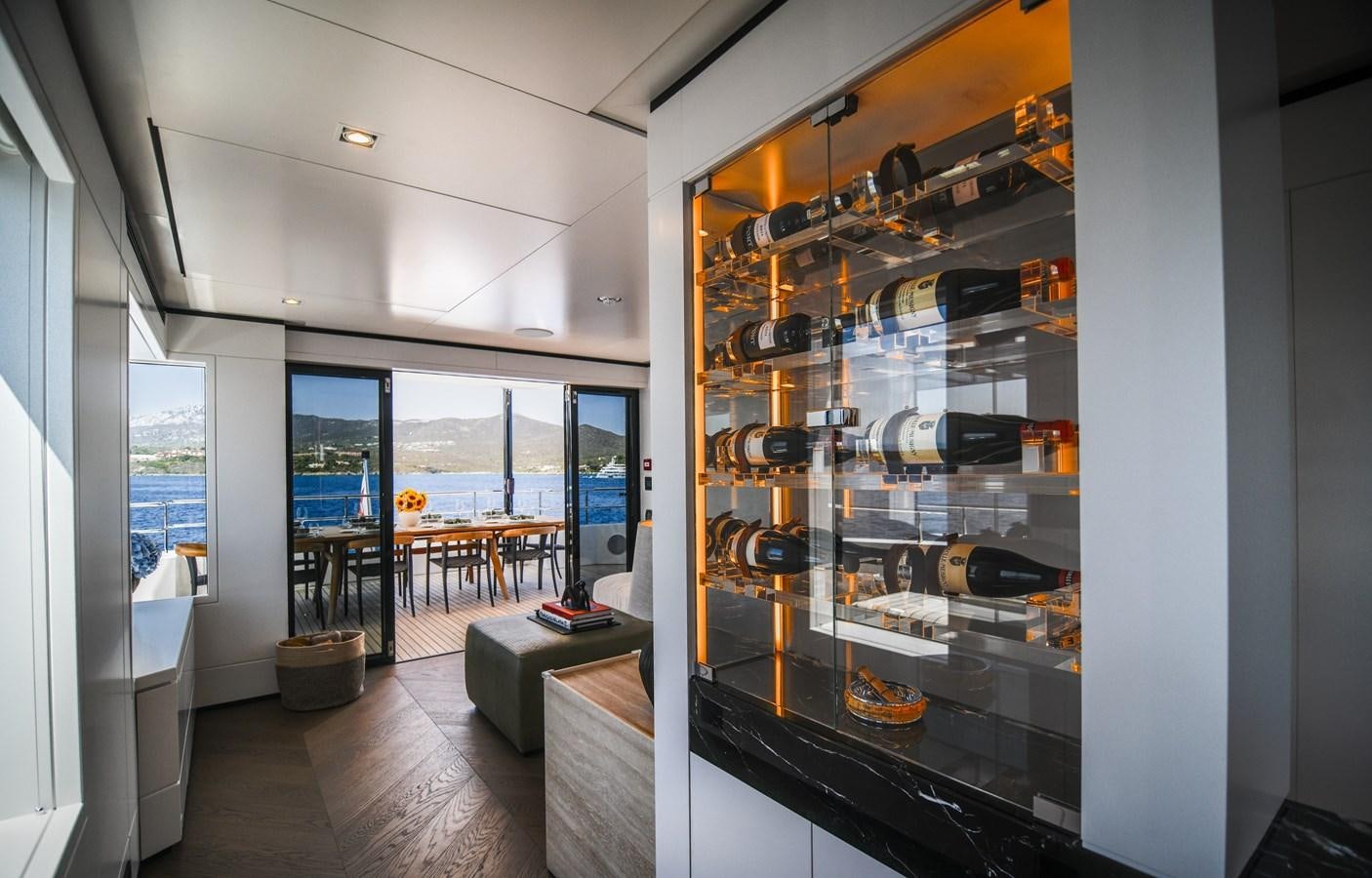 a room with a large glass display case and a table with chairs aboard FOX Yacht for Sale