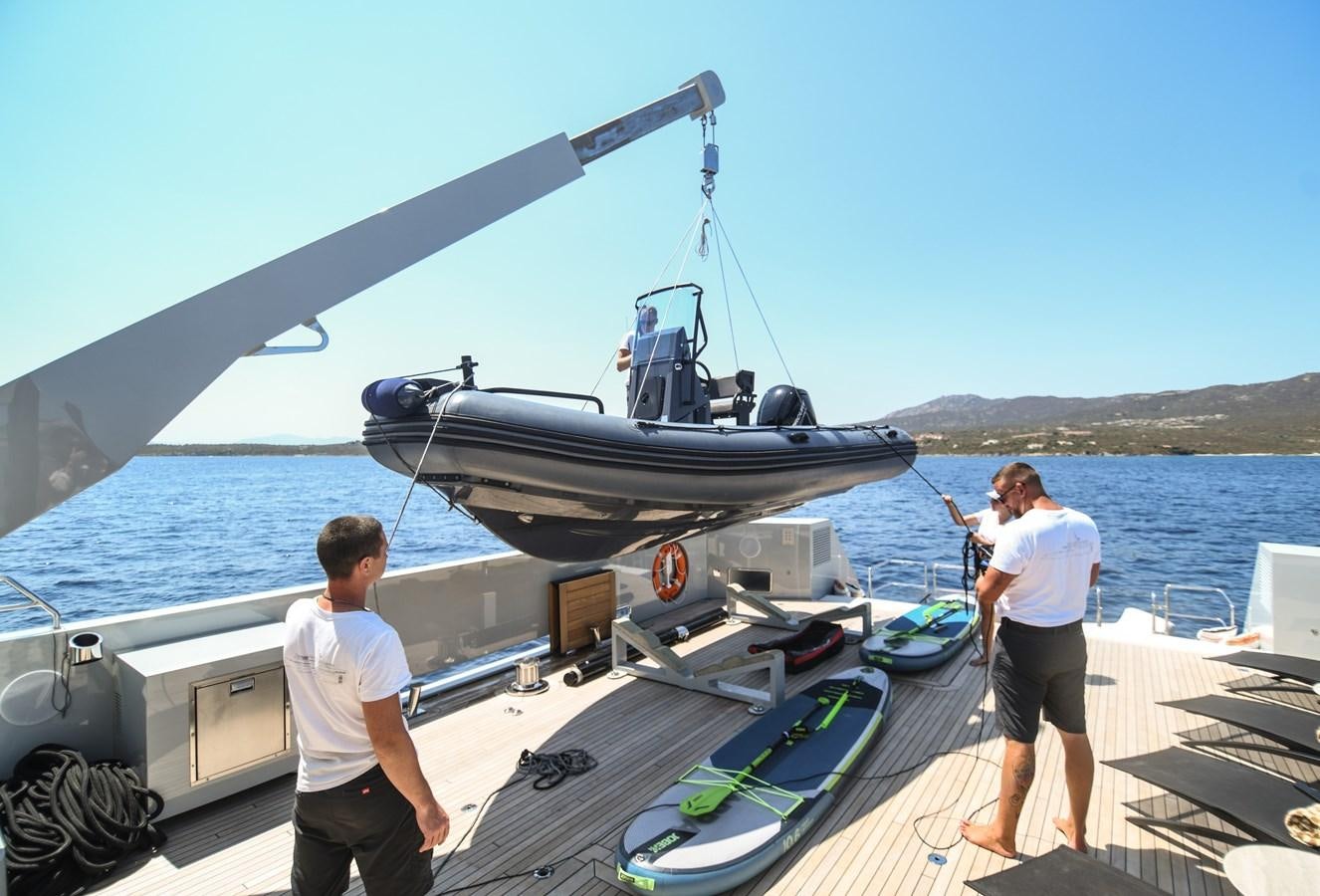 a couple of men standing on a boat with a helicopter on the deck aboard FOX Yacht for Sale