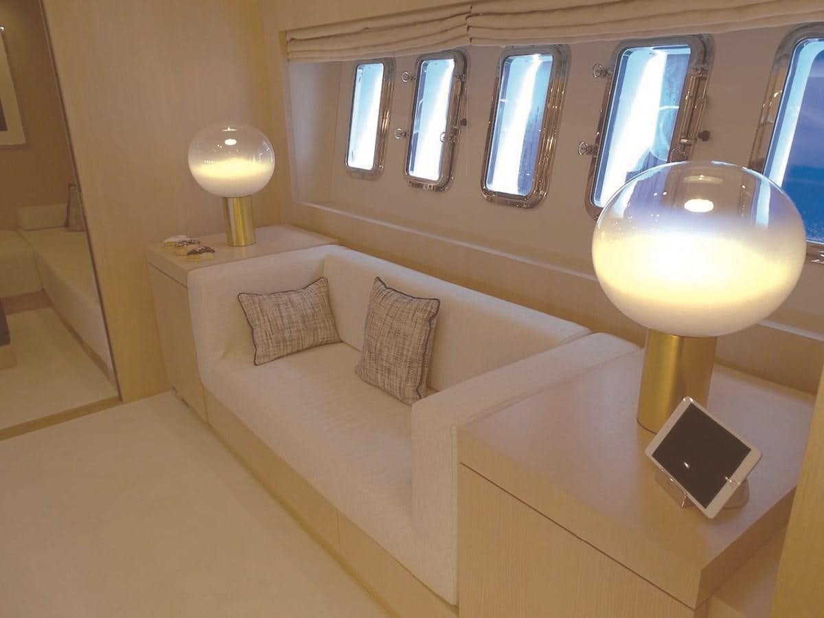 a bed with a white bed and a round lamp aboard TOTAL Yacht for Charter