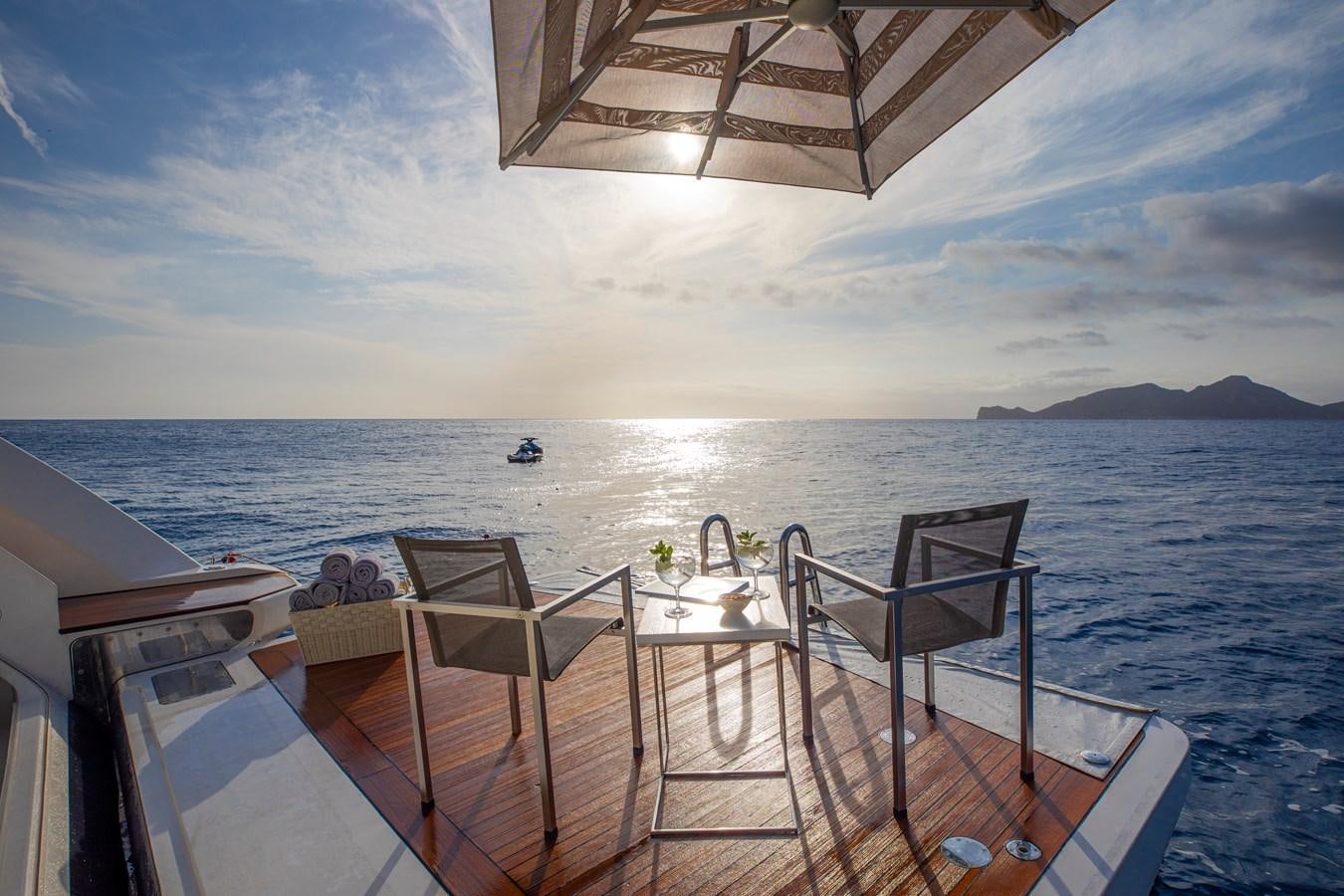a deck with chairs and a table on it by the water aboard ORSO 3 Yacht for Sale
