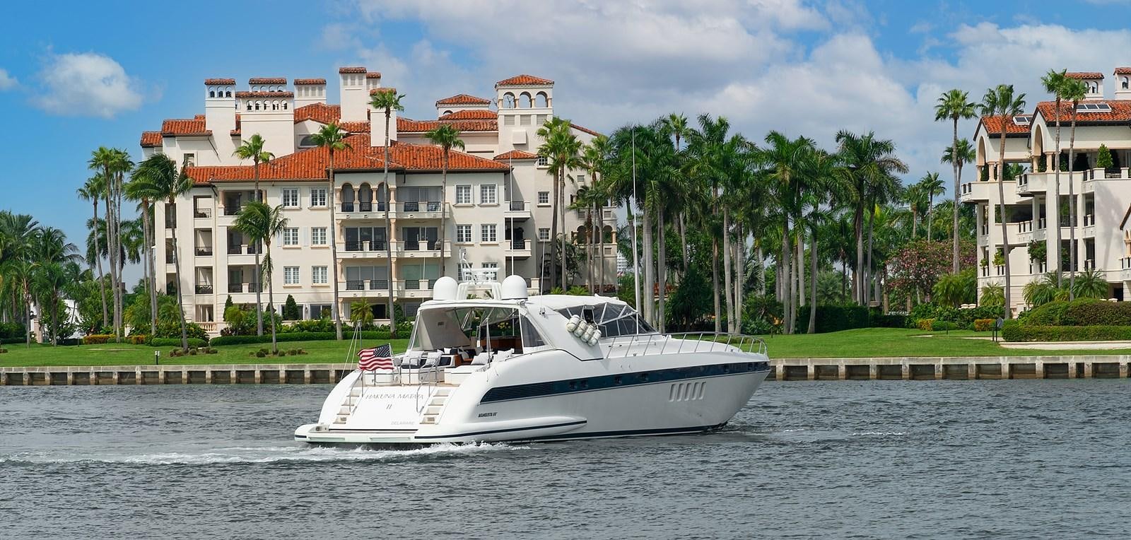 a white boat on the water with Fisher Island in the background aboard HAKUNA MATATA Yacht for Sale