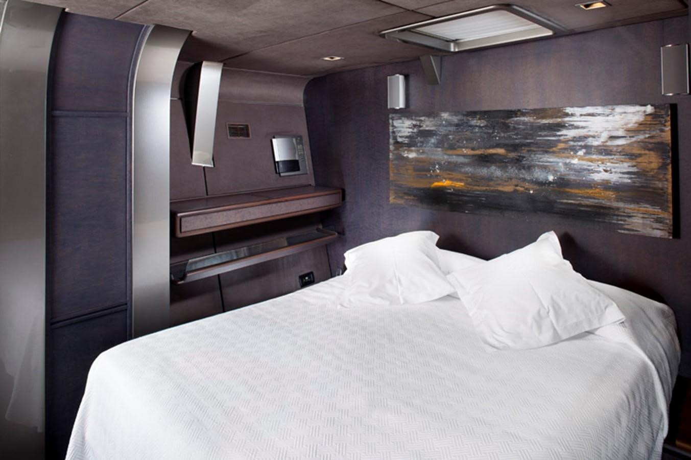a bed with a white sheet and a television on the wall aboard SYL Yacht for Sale
