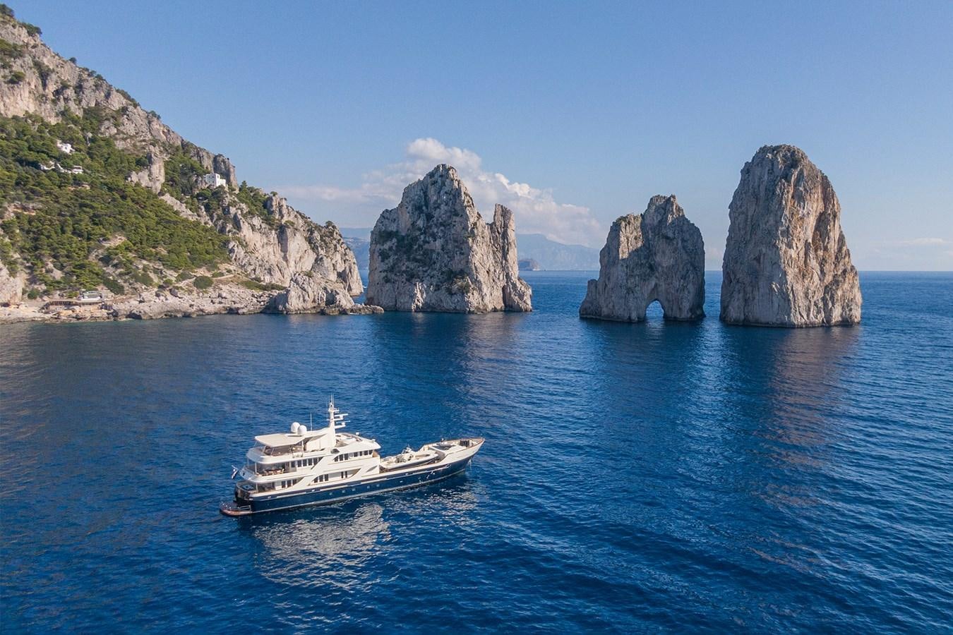 a boat in the water with Capri in the background aboard LIBERTA Yacht for Sale
