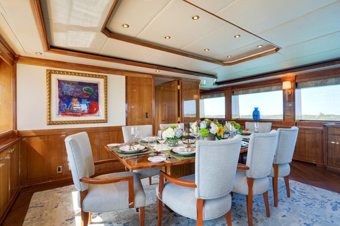 a dining table and chairs in a room with a large window aboard TEMPTATION Yacht for Sale