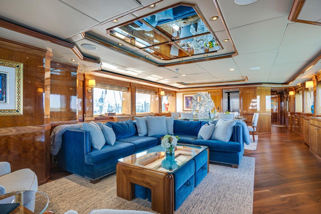 a living room with a blue couch aboard TEMPTATION Yacht for Sale