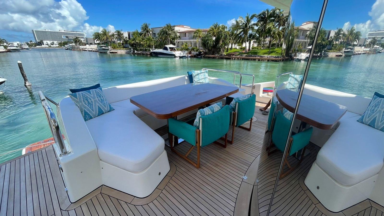 a deck with chairs and tables on it by a body of water aboard VICTORIOUS Yacht for Sale