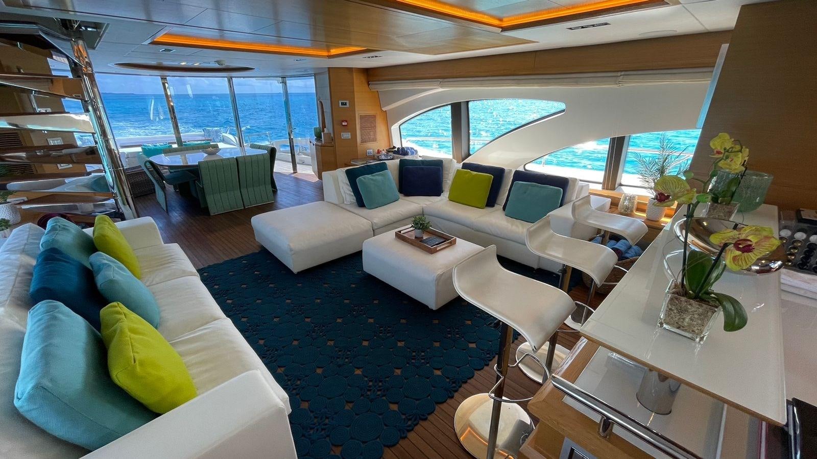a room with a large blue and white rug and a white table with green pillows and a white aboard VICTORIOUS Yacht for Sale