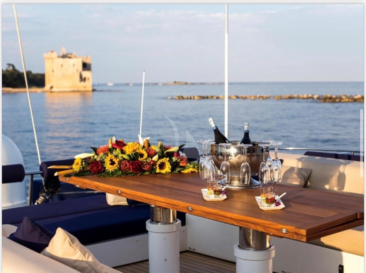 a table with glasses and flowers on it by a body of water aboard MANTANI Yacht for Sale