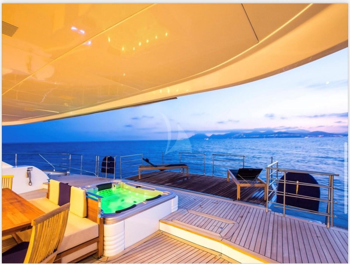 a deck with a view of the ocean and the mountains in the background aboard MANTANI Yacht for Sale