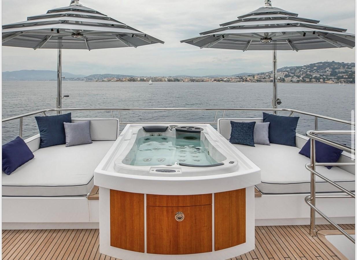 a white lounge chair next to a white bed and a large white umbrella aboard MILLESIME Yacht for Charter
